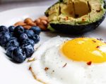 A fried egg, blueberries, almonds, and an avocado