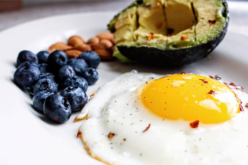 A fried egg, blueberries, almonds, and an avocado