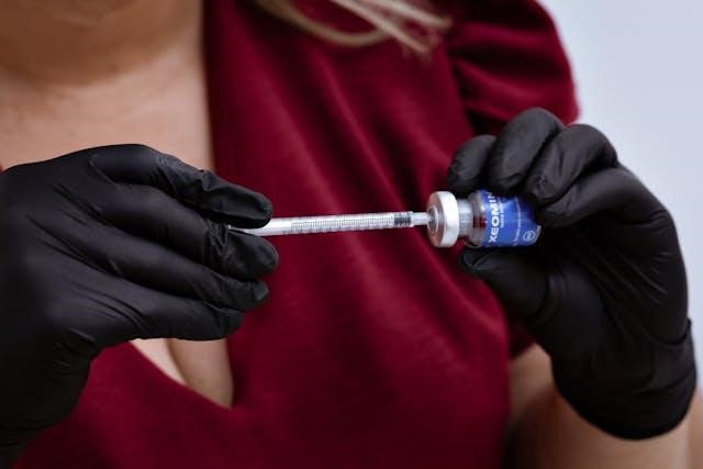 A medical professional with black gloves preparing a botox injection